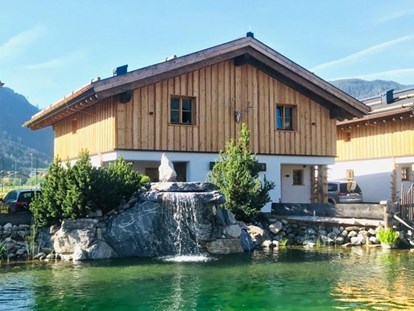 Hüttendorf - Mallnitz - Eines unserer Chalet Hütten mit unserem Naturschwimmteich davor.  - Sieglhub Chalets Appartements Hotel