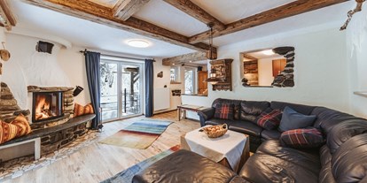 Hüttendorf - Schwerpunkt: Familienurlaub - Kärnten - Smileys Wohnzimmer mit Ofenen Feuer und Blick auf den Fluss - Smileys Fluss Chalet